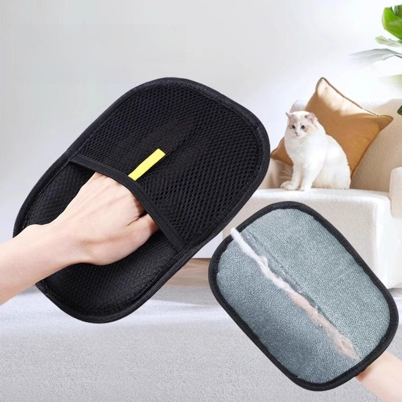 Black mesh furniture hair removal glove with grey scrubber side, held by a person, with a white cat in the background.