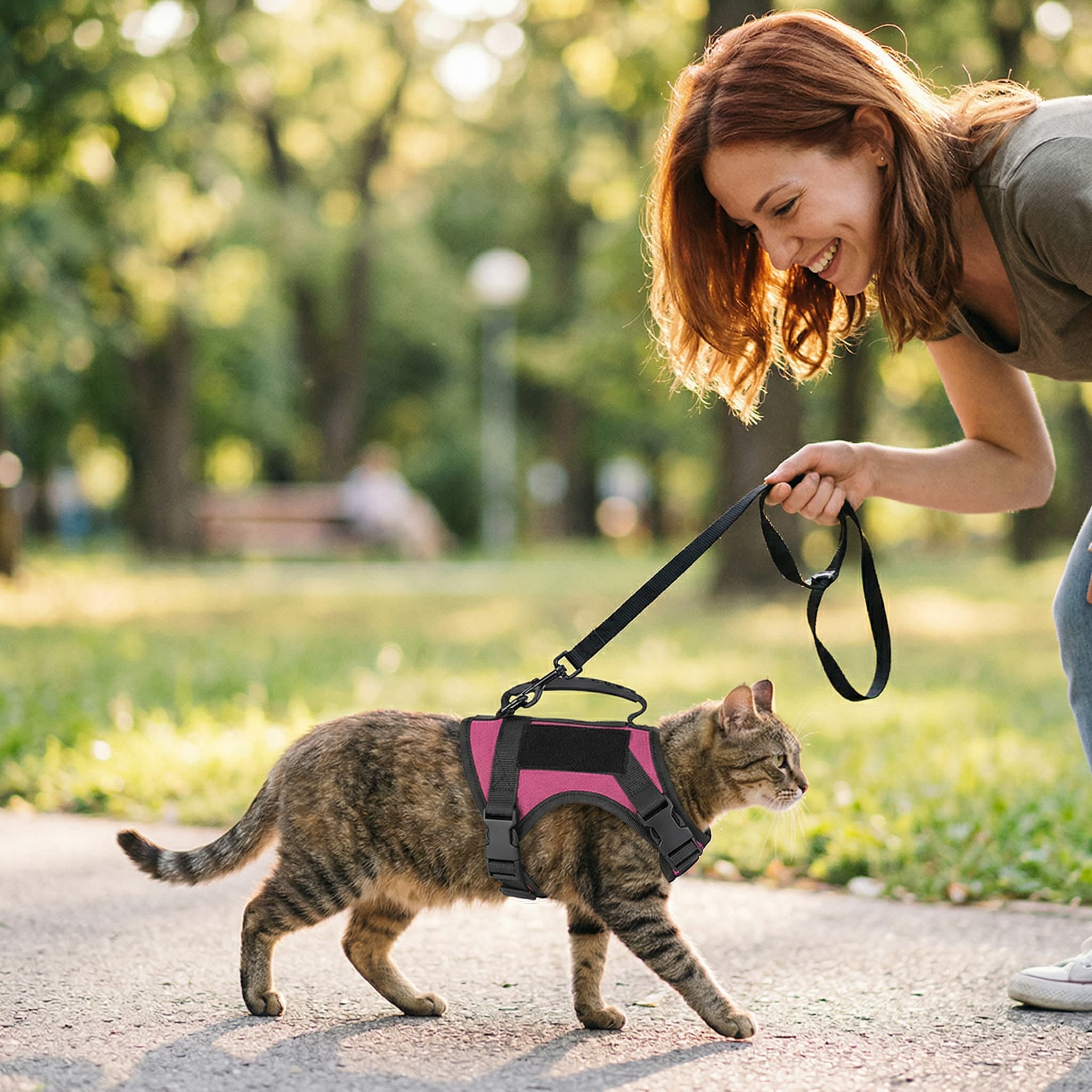 Woman walking a cat on a leash in a park