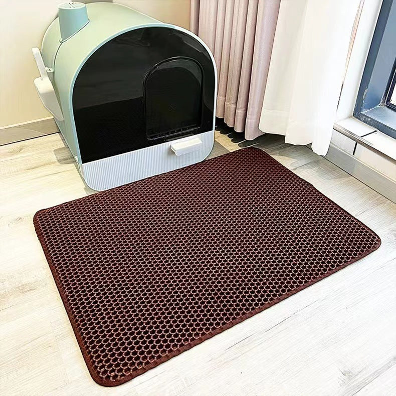 Brown honeycomb mat in front of a cat litter box on a light wood floor.