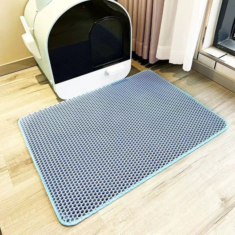 Blue mat with textured surface in front of a white litter box on a wooden floor.