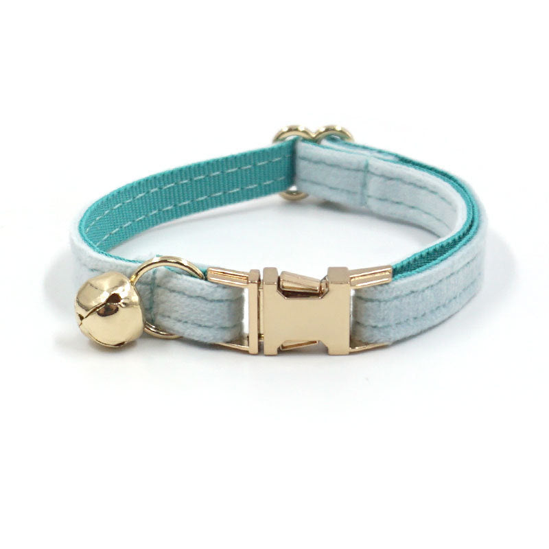 Dog collar with gold bell and blue and gray pattern on a white background