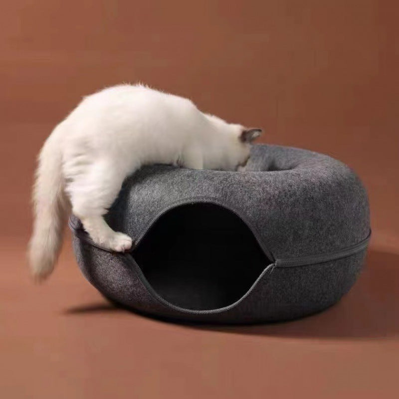 White cat climbing into a gray pet bed on a brown background
