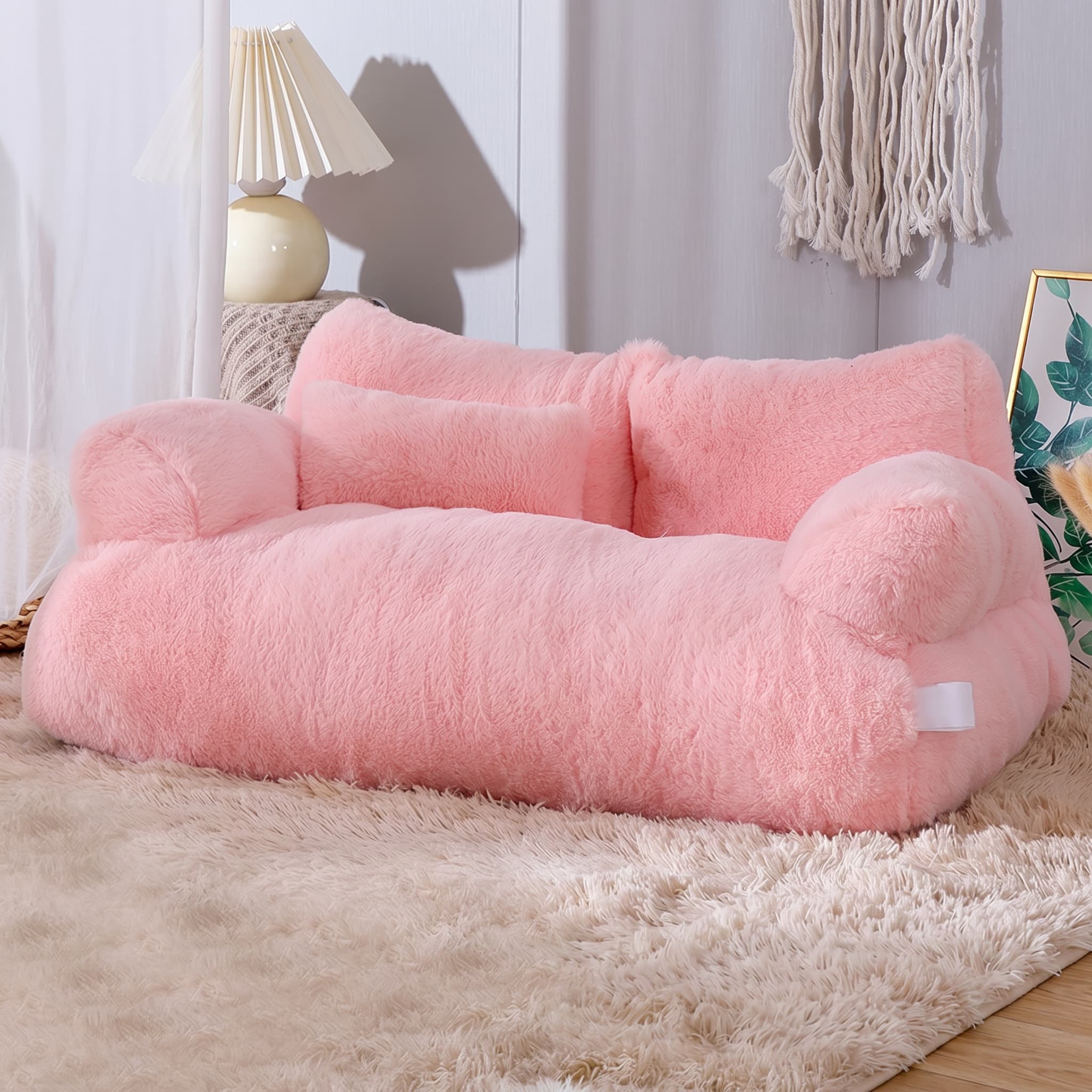 Pink pet bed on a beige carpet with a lamp and decorative items in the background