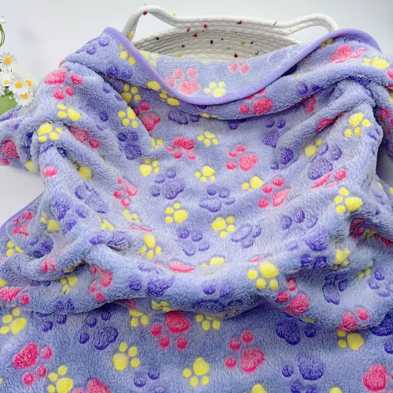 Folded purple pet blanket with colourful paw prints on a white background