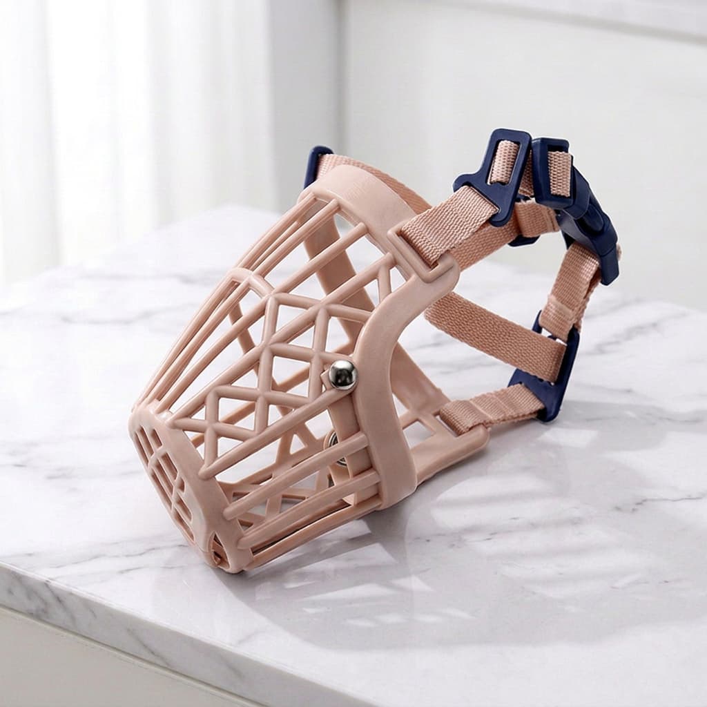 A beige dog muzzle with a geometric open-frame design and adjustable navy blue straps, displayed on a white marble surface.