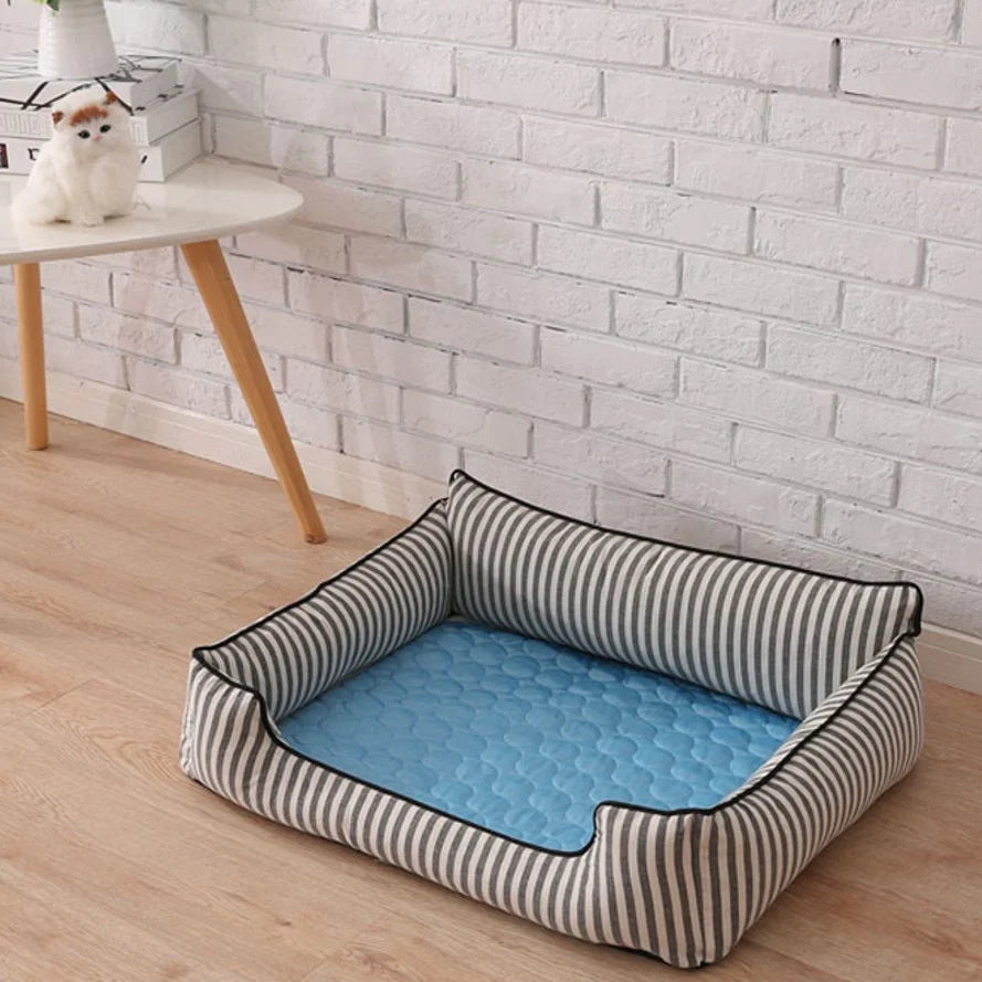 Striped pet bed with pet self cooling mat inside on a wooden floor against a white brick wall.