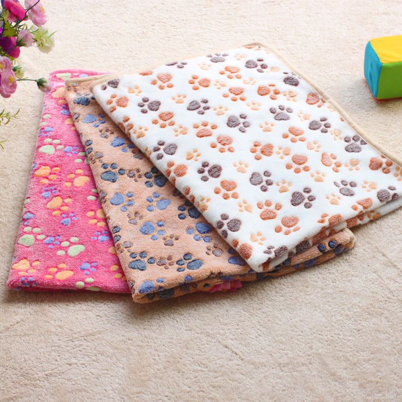 Three pet blankets with paw print patterns on a beige surface.