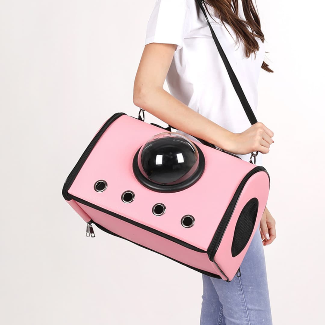 Person holding a pink pet carrier with a transparent dome on a white background