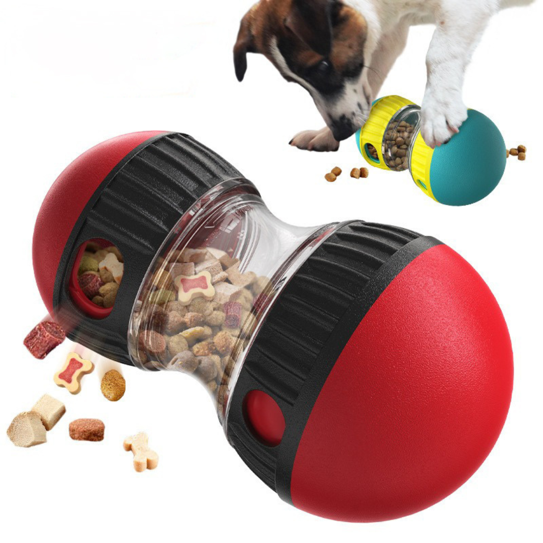 Red and black dog toy with transparent center containing treats, accompanied by a dog interacting with a colorful toy in the background.