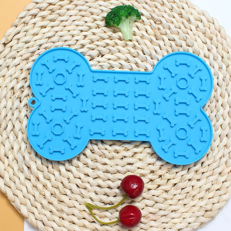 Blue bone-shaped pet toy on a woven mat with vegetables