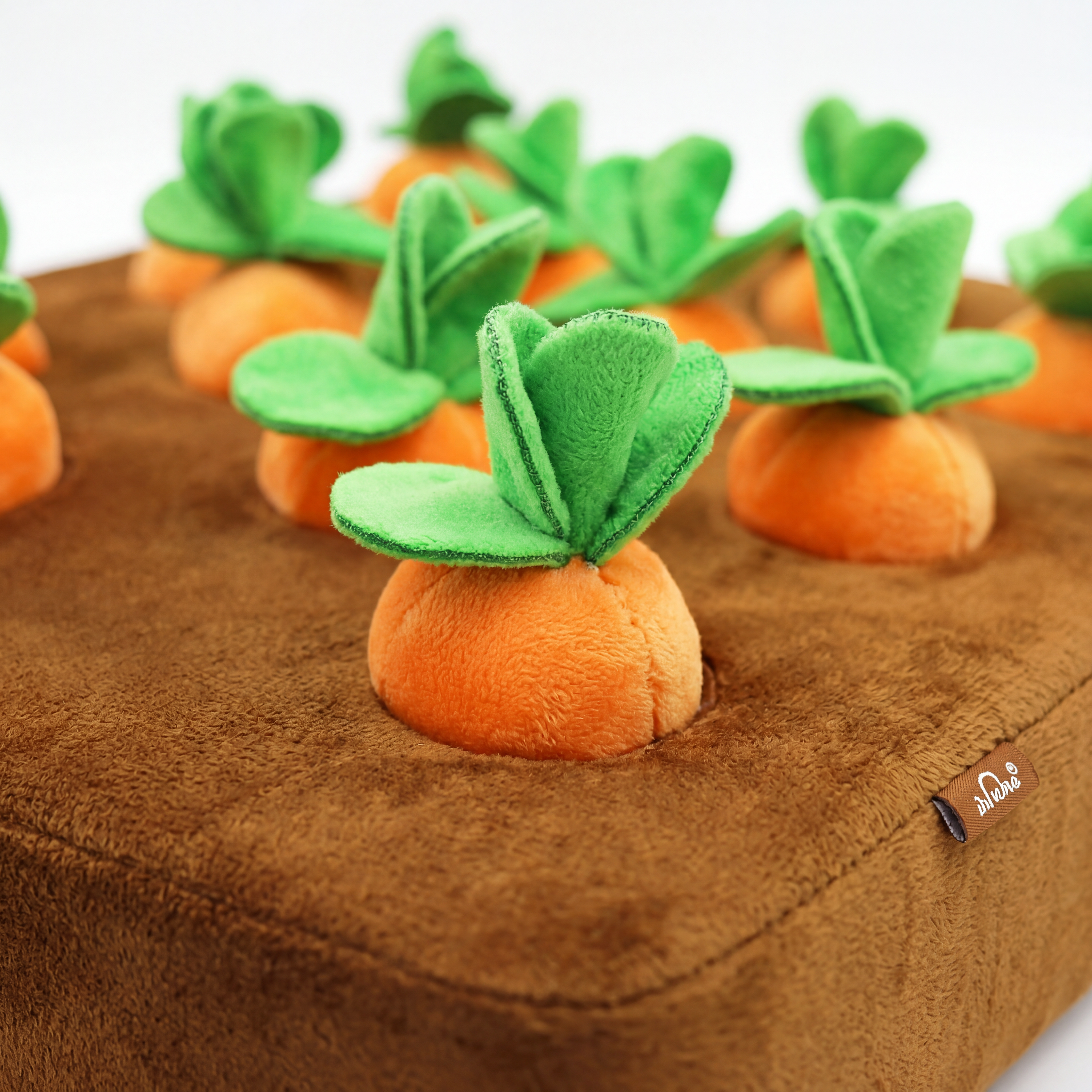 Plush carrot toys with green leaves on a brown surface