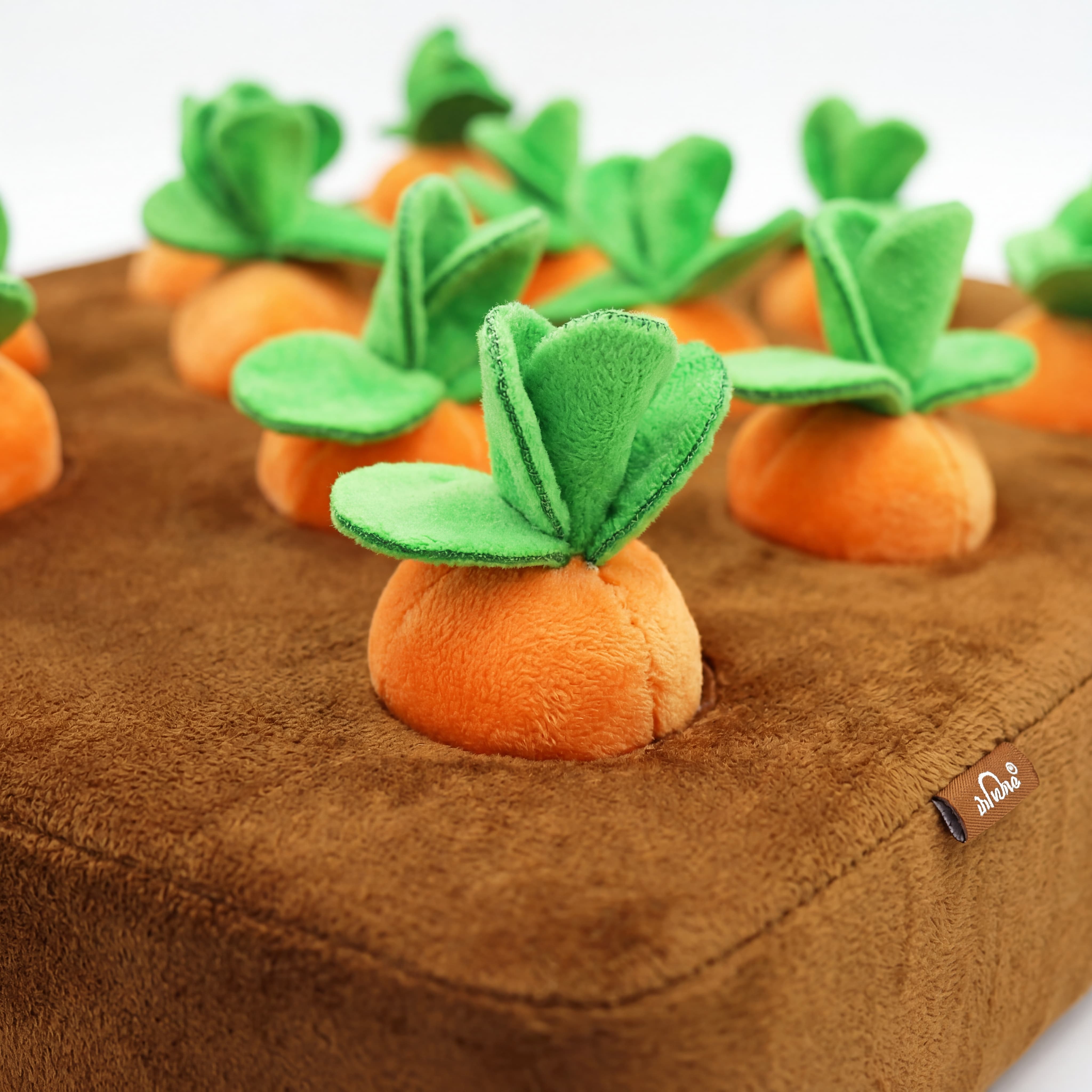 Plush carrot toys with green leaves on a brown surface