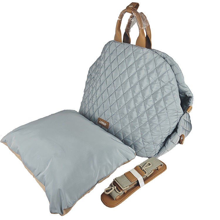 Quilted baby carrier with pillow and straps on a white background
