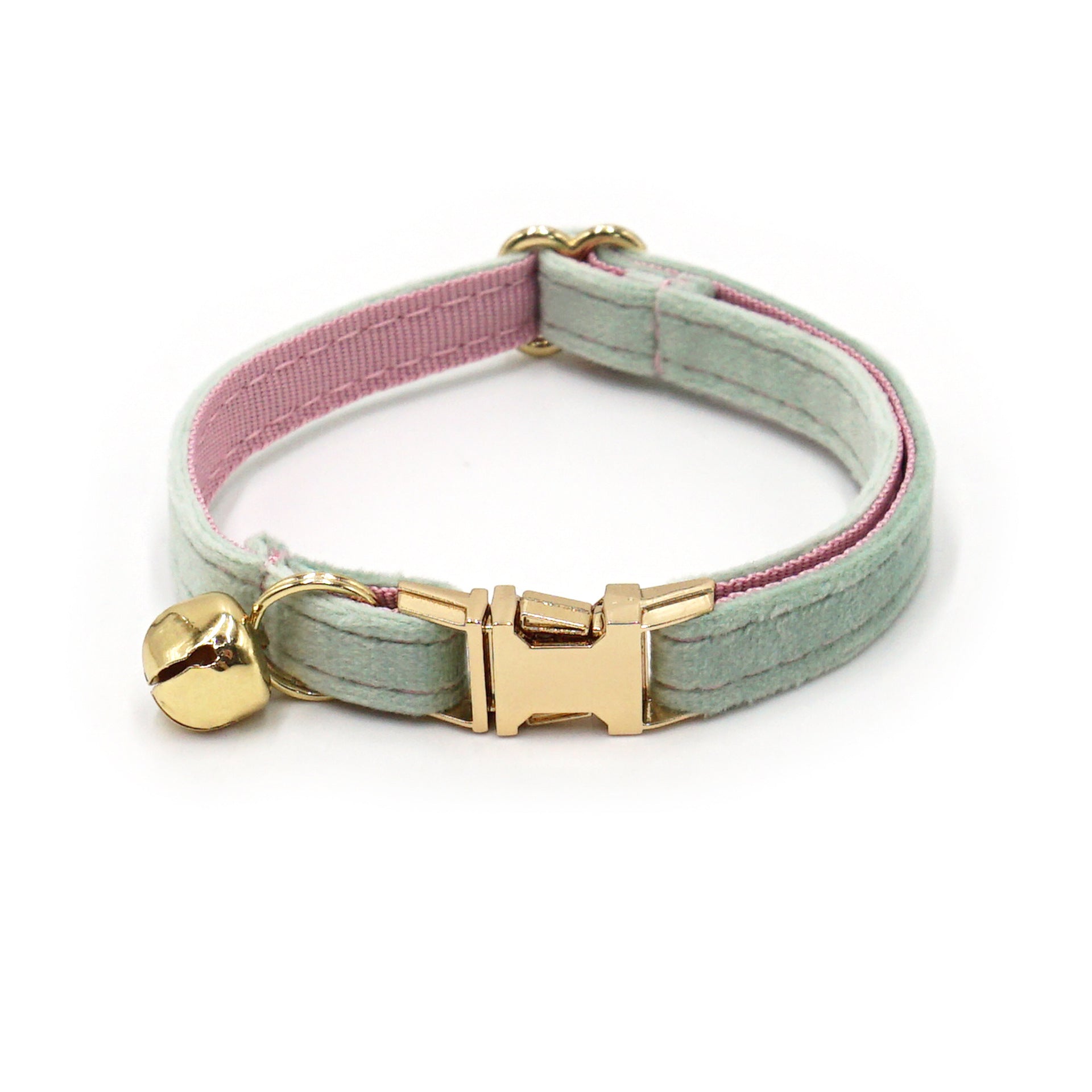 Cat collar with gold bell and pink interior on a white background