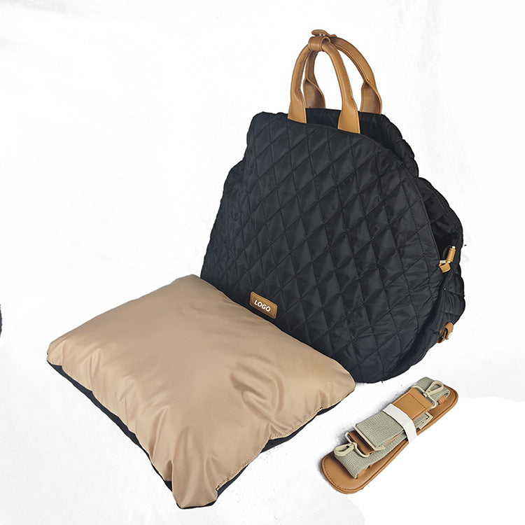 Black quilted backpack with beige pillow and strap on a white background