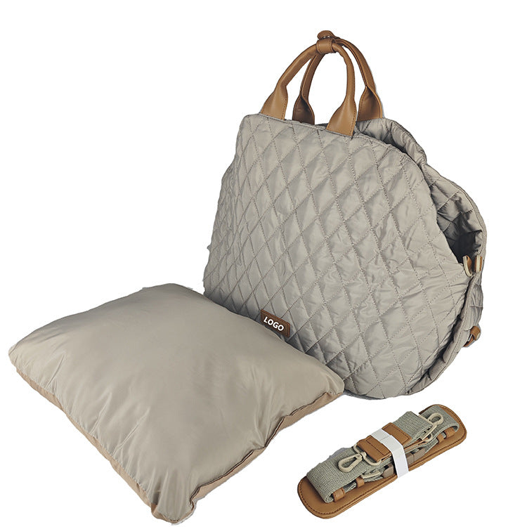 Quilted brown bag with brown handles, matching pillow, and rolled-up mat on a white background