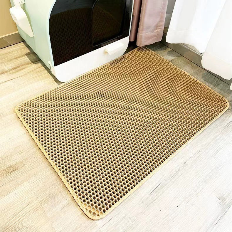 Beige litter mat with honeycomb pattern on a wooden floor.