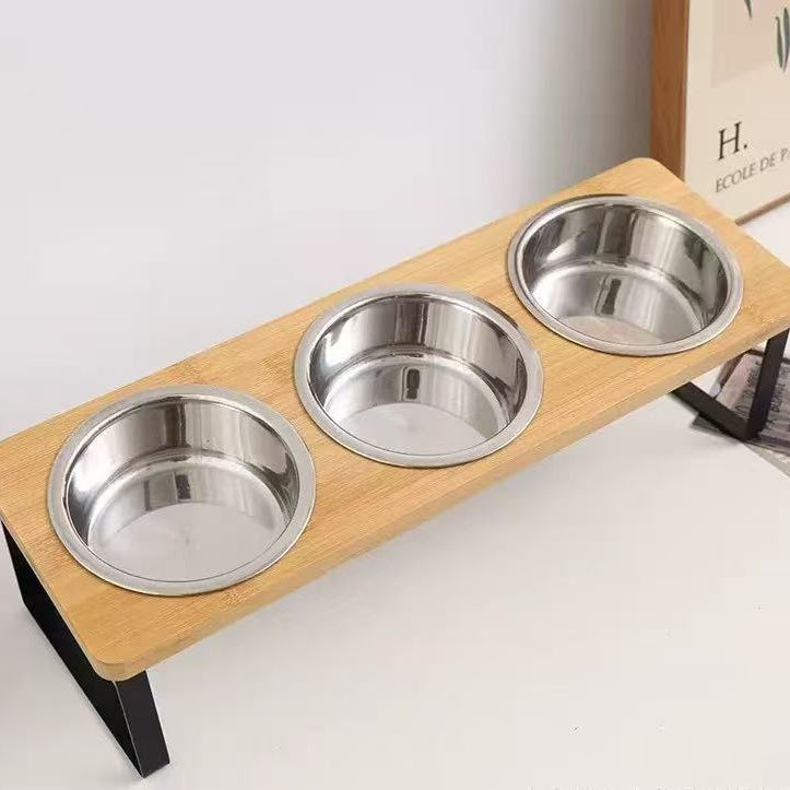 Wooden pet feeder with three metal bowls on a white surface