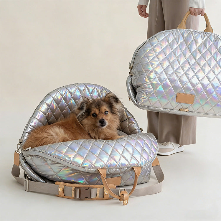 Dog lying in a silver quilted pet carrier with a matching travel bag on a light background