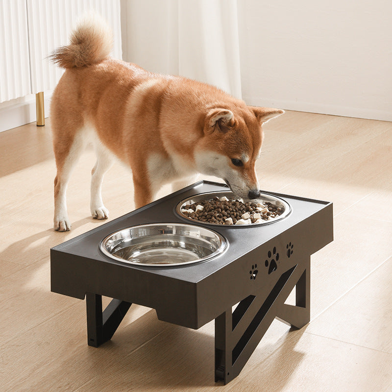 Dog eating from a elevated pet feeder with two bowls on a wooden floor.