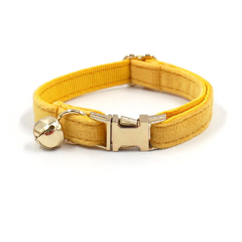 Yellow dog collar with a gold buckle and bell on a white background