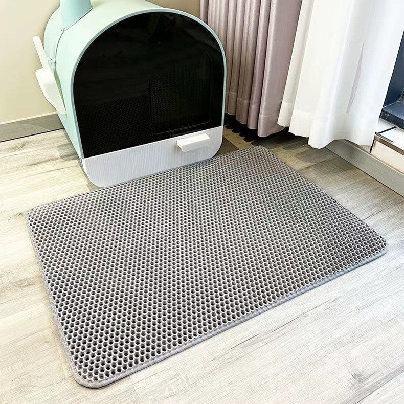 Grey litter mat in front of a white pet bed on a wooden floor.