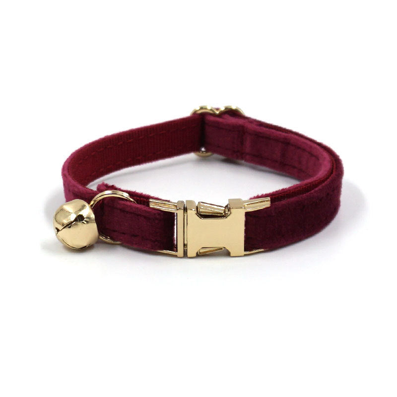 Burgundy velvet dog collar with gold hardware on a white background