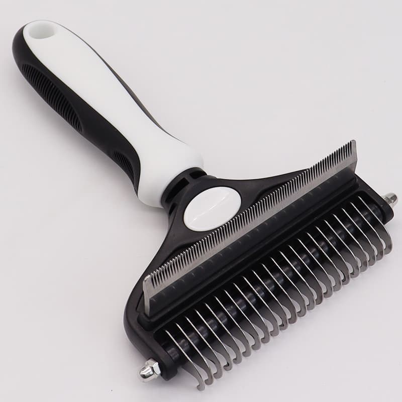 Pet grooming brush with black and white handle on a light gray background