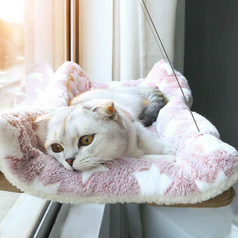 Cat lounging on a fluffy pink cushion with cat tree in the background