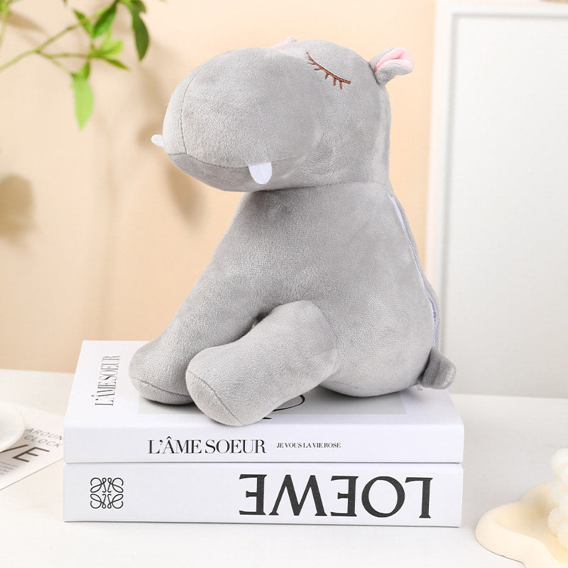 Grey plush hippo toy on a book with a blurred background
