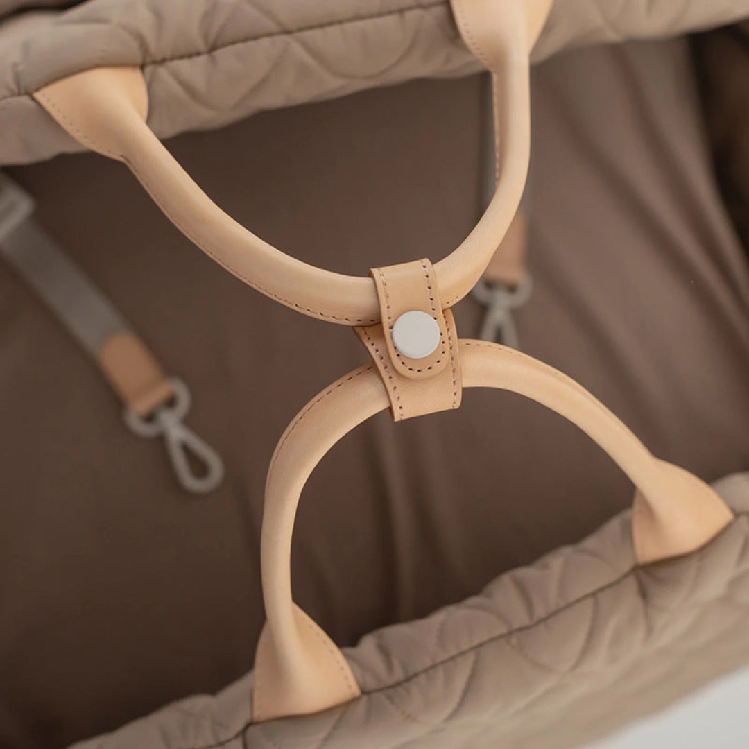 Close-up of a brown baby carrier with leather straps on a brown background