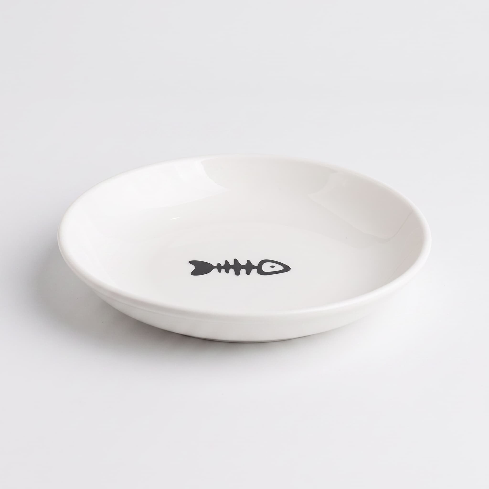 A white ceramic shallow bowl featuring a minimalist black fish skeleton graphic printed in the center, set against a clean white background.
