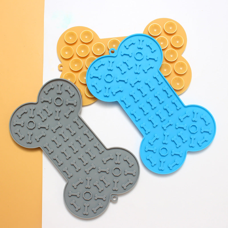 Three bone-shaped silicone mats in blue, grey, and yellow on a white background.