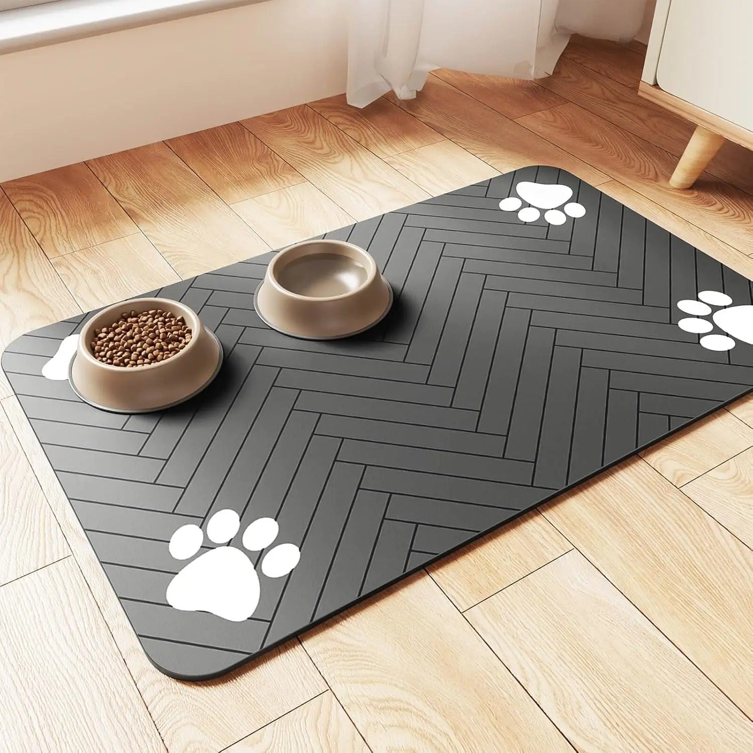 Grey pet mat with paw prints on a wooden floor with two bowls of food.