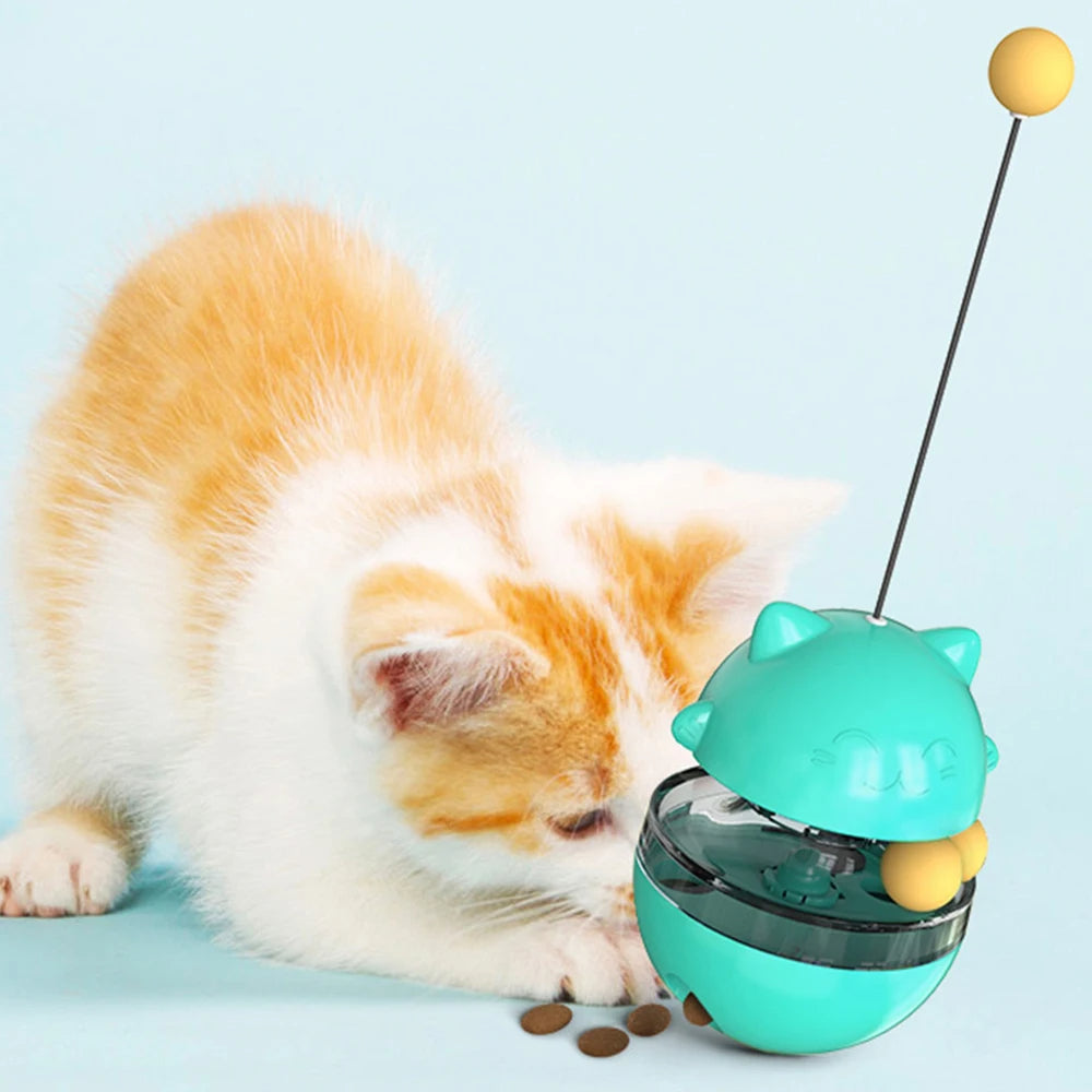Cat playing with a teal toy that has a yellow ball on top against a light blue background