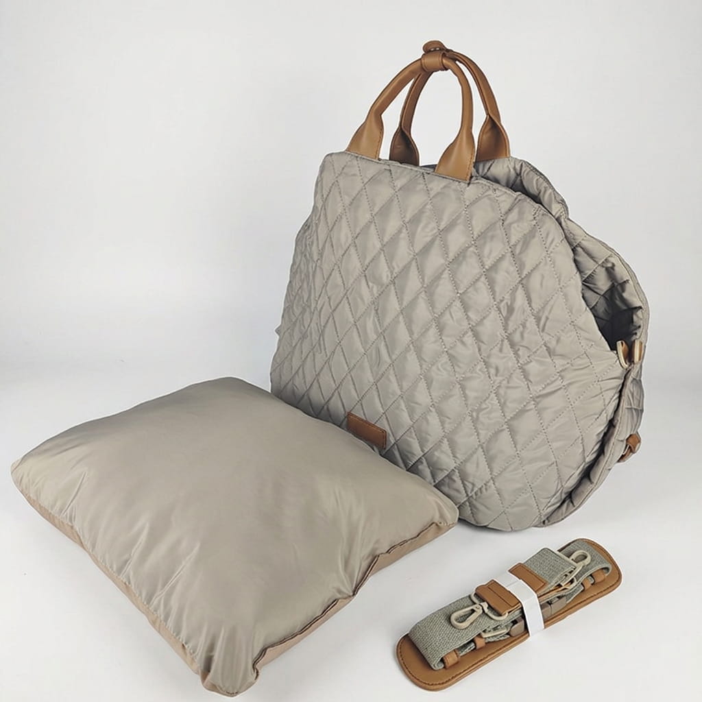 A quilted light grey dog handbag carrier set shown with a matching pillow and a rolled-up brown strap, photographed on a clean white studio background.